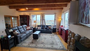 Un salon avec un canapé en cuir, une table basse, un tapis, un meuble en bois et un téléviseur.