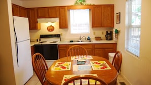 A kitchen with wooden cabinets, a stove, a refrigerator, and a dining table with chairs. - The Wildlife Hot Tub Cabin @ LakePointe Resort - no cleaning fees!  (Russell Springs)