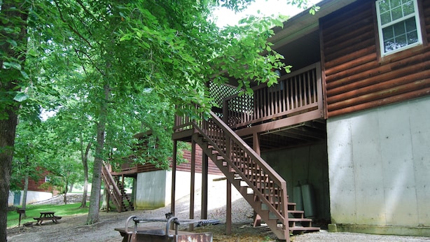 A rustic cabin with a wooden staircase leading to a deck, surrounded by trees. - The Wildlife Hot Tub Cabin @ LakePointe Resort - no cleaning fees!  (Russell Springs)