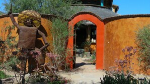 Un bâtiment rustique doté d’une entrée en arc de cercle, entouré de verdure et agrémenté d’une sculpture décorative.