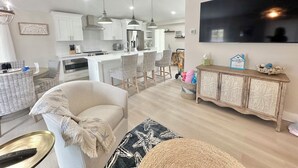 Une cuisine moderne avec des meubles blancs, un grand îlot central et des luminaires suspendus.