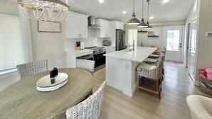 Une cuisine moderne avec des meubles blancs, un îlot central et des luminaires suspendus.