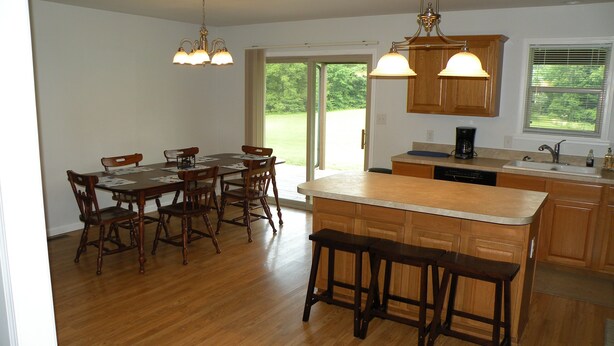 A spacious kitchen with wooden cabinetry, a central island with stools, and pendant lighting.