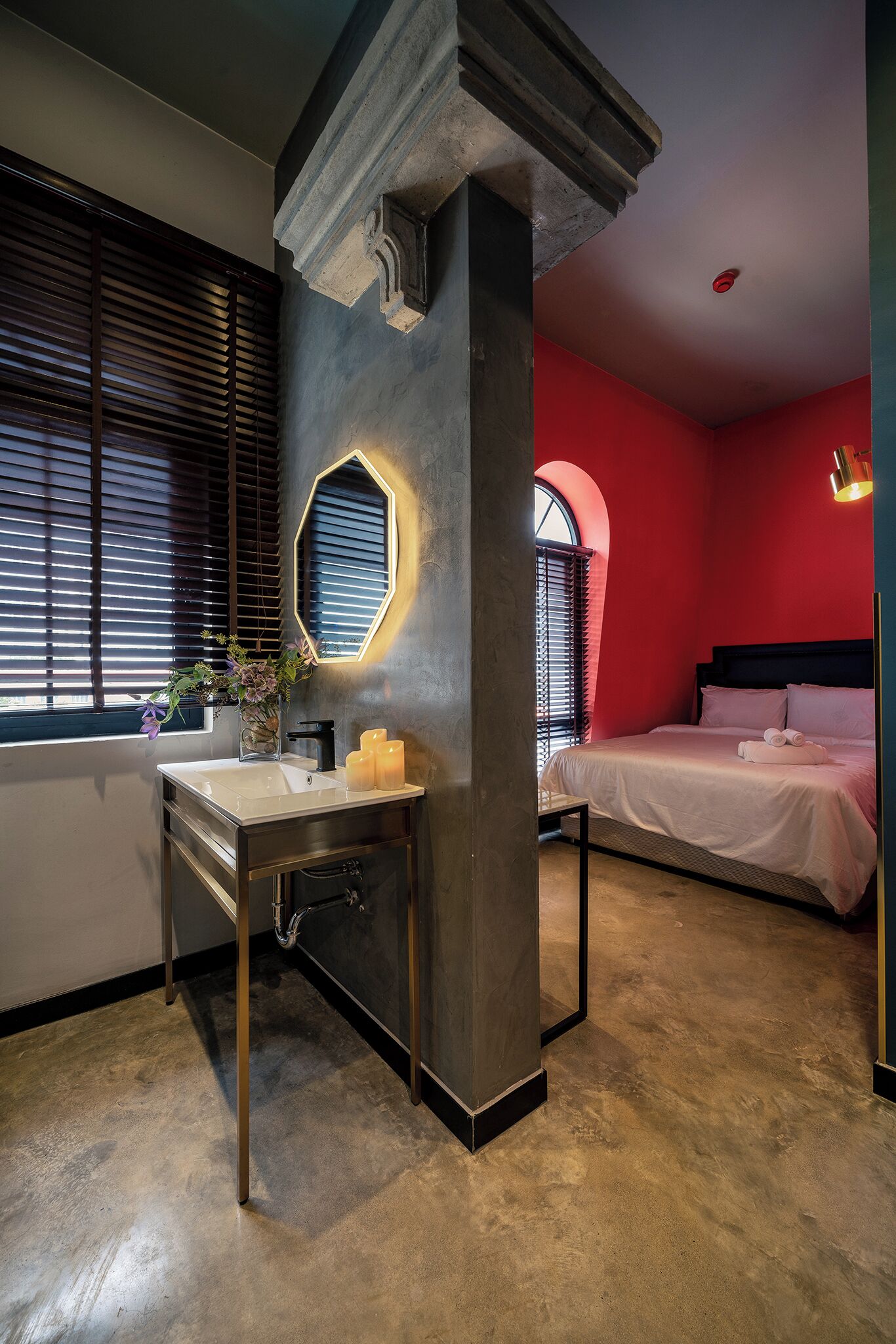Una camera d'albergo moderna con un letto grande, una toeletta con specchio e una finestra con persiane.