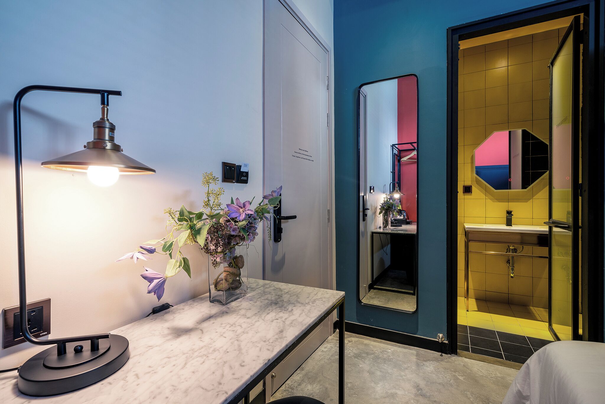 Un baño moderno con encimera de mármol, espejo montado en la pared y zona de ducha visible.