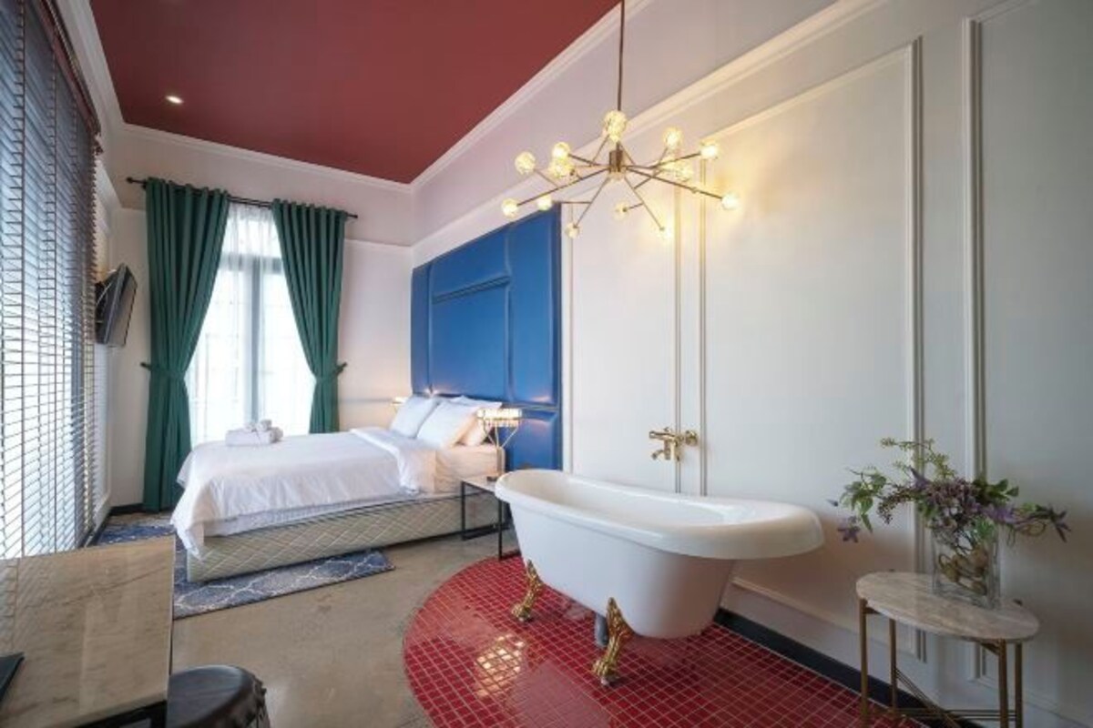 Une chambre moderne avec un grand lit, une baignoire et un mur d’accent bleu.