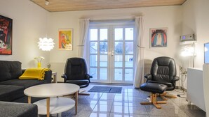 Een woonkamer met een bank, twee stoelen, een salontafel en kunstwerken aan de wanden.