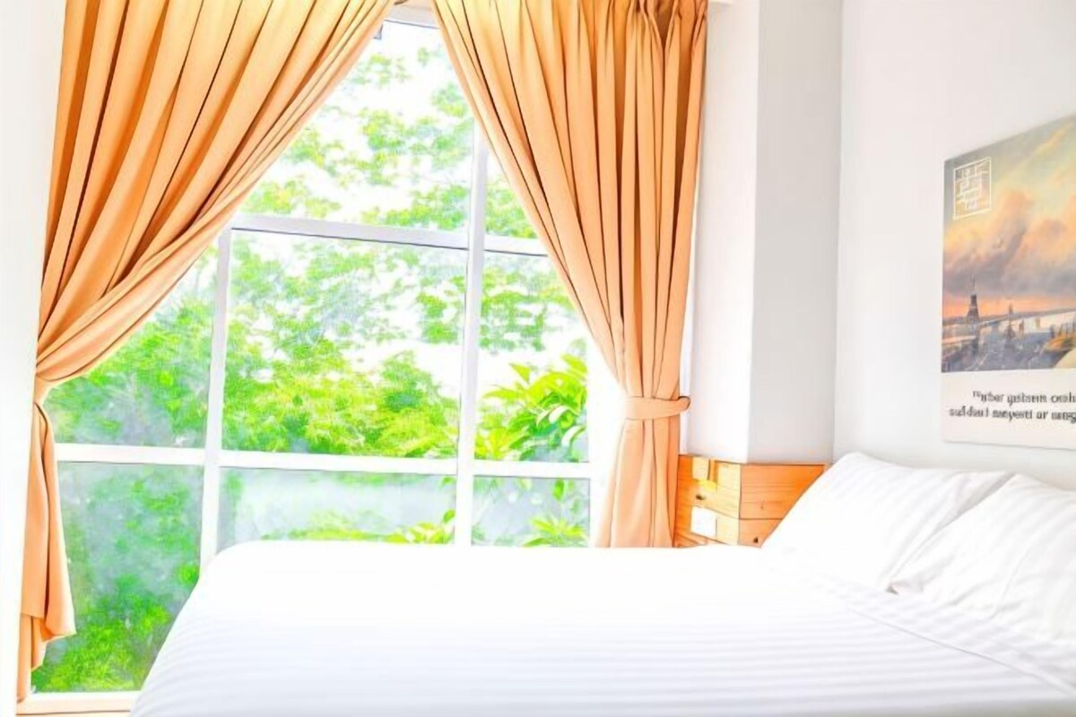 Quarto com uma janela grande, cortinas, cama e prateleira na parede.