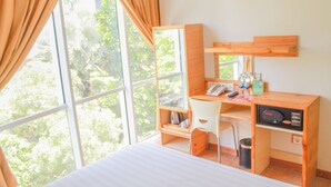 A room with a bed, a desk with a computer, a chair, and a window with curtains. - An Hotel Satrio Kuningan (Jakarta)
