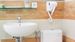 A bathroom with a white sink, toilet, and a towel rack with an orange towel. - An Hotel Satrio Kuningan (Jakarta)