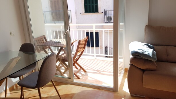 Un balcon avec une porte vitrée, des meubles en bois et un canapé beige.