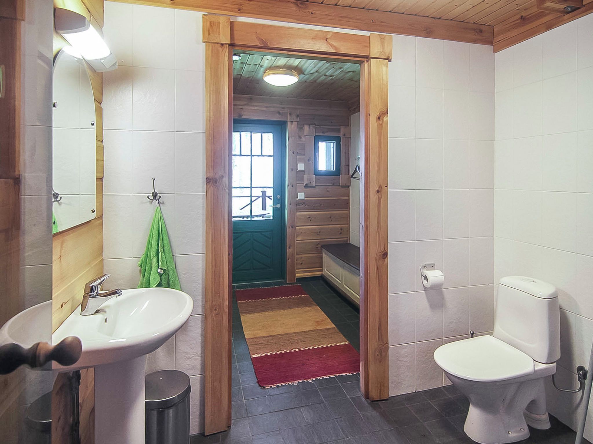 Un bagno con una porta in legno, un lavandino, un water e uno specchio.
