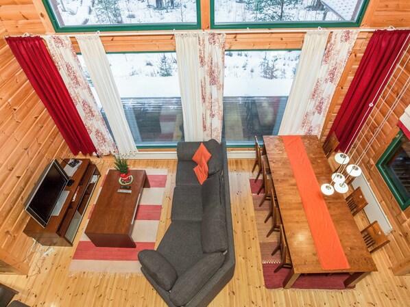 Un interior de cabaña acogedor con sofá, mesa de comedor y chimenea.