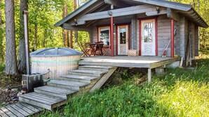 Eine Hütte mit überdachter Terrasse, Whirlpool und Tisch mit Stühlen außen.