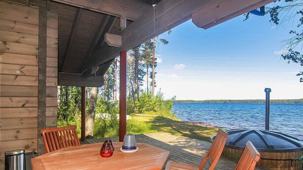 Eine Holzterrasse mit Tisch und Stühlen mit Blick auf einen See.