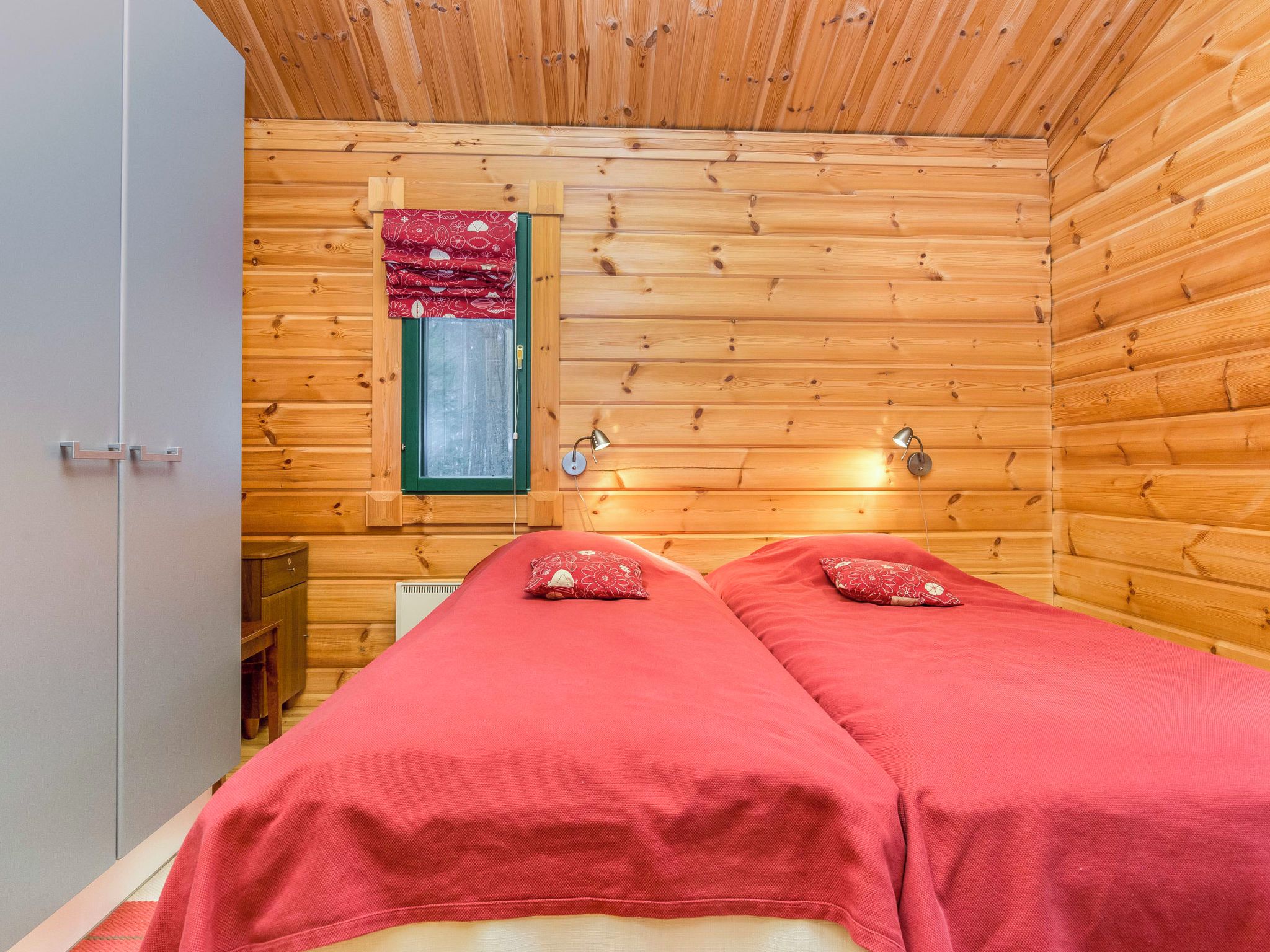 Una habitación de cabaña de madera con dos camas, una ventana y una puerta.