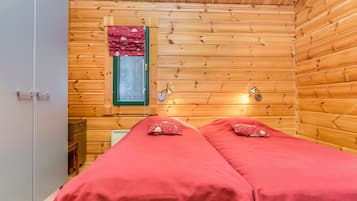 Una habitación de cabaña de madera con dos camas, una ventana y una puerta.