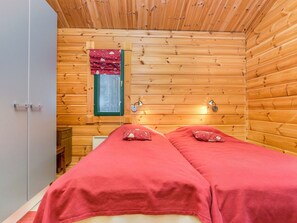 Une pièce de cabane en bois avec deux lits, une fenêtre et une porte.