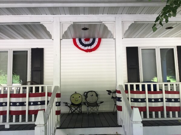 En veranda med hvid gelænder, to stole og et dekorativt amerikansk flag.