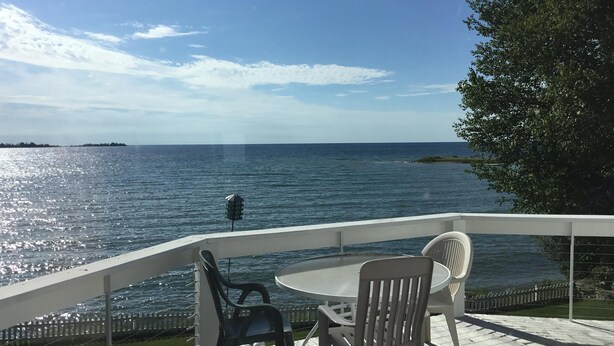 A deck with a table and chairs overlooking a body of water, with a distant island visible. - Waterfront Home In Baileys Harbor ~ Fantastic Views Of The Harbor And Islands! (Baileys Harbor)