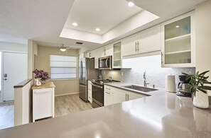 A modern kitchen with white cabinetry, stainless steel appliances, and a large island.
