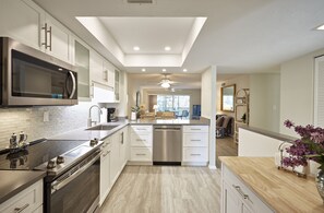 A modern kitchen with a central island, stainless steel appliances, and a ceiling fan.
