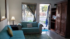 Una sala de estar con un sofá, una lámpara, un tapete y un armario.