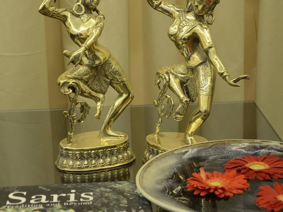 Dos estatuas doradas sobre una superficie reflectante, junto a un libro con el título