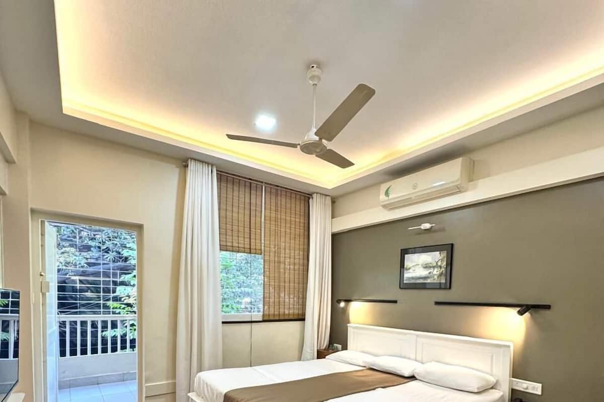 A bedroom with a bed, bedside table, ceiling fan, and a window with curtains.