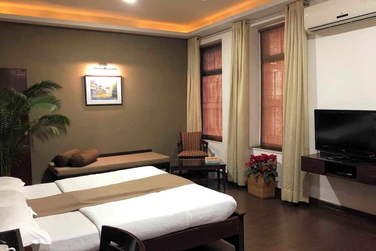 A hotel room with a large bed, a television, a desk, and a chair.