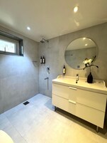 Un baño moderno con un espejo grande, un lavabo y una ducha.