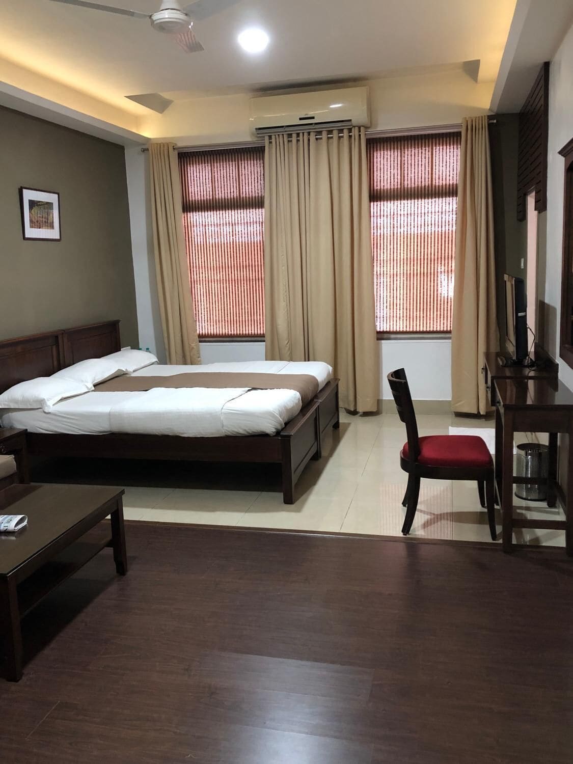 A hotel room with a bed, a desk, a chair, and a ceiling fan.