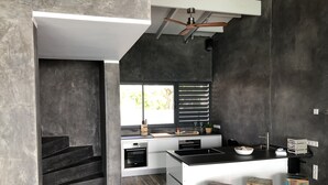 Una cucina moderna con forno integrato, lavello e finestra con persiane.