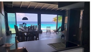 Una cucina moderna con un'isola grande, una zona pranzo vista oceano e un'area salotto con poltrone.