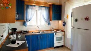 Una cocina con armarios azules, un refrigerador blanco, una estufa y un fregadero.