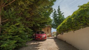 Un estrecho sendero empedrado que conduce a un coche rojo estacionado junto a un edificio con vestíbulo cubierto.