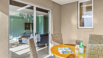 A room with a glass door leading to a balcony, a round wooden table with chairs, and a bottle of water.