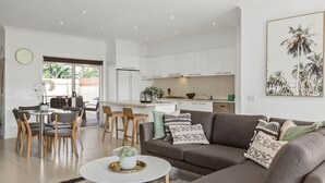 Un salon moderne avec un canapé gris, une table basse et un coin repas comprenant des chaises en bois et une table en verre.