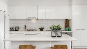 Une cuisine moderne avec des meubles blancs, un grand îlot central et une cuisinière à gaz.