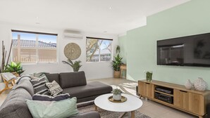 Un salon moderne avec un canapé gris, une table basse blanche et un meuble TV en bois.