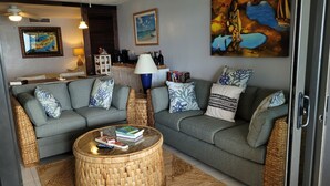 A cozy living room with two grey sofas, a round wicker coffee table, and a bookshelf. - Scenic Ocean front walk-out~fully renovated~property wide generators  (St Thomas, USVI)
