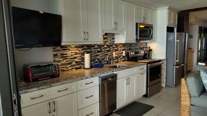 A modern kitchen with white cabinets, a black microwave, a stainless steel refrigerator, and a built-in oven. - Scenic Ocean front walk-out~fully renovated~property wide generators  (St Thomas, USVI)