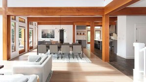 A spacious living area with a dining table, sofas, and a kitchen in the background. - Luxury golf course chalet with hot tub (Whistler)