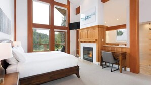 A bedroom with a large bed, a fireplace, a desk, and a view of the outdoors. - Luxury golf course chalet with hot tub (Whistler)
