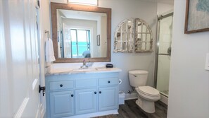 Ein Badezimmer mit hellblauem Waschtisch, einer weißen Toilette und einer Duschkabine aus Glas.