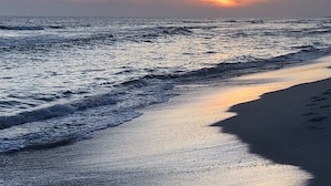 Une plage avec des vagues au coucher du soleil.
