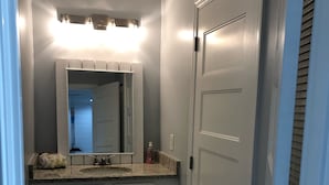 A bathroom with a vanity, a mirror, a sink, and a door.