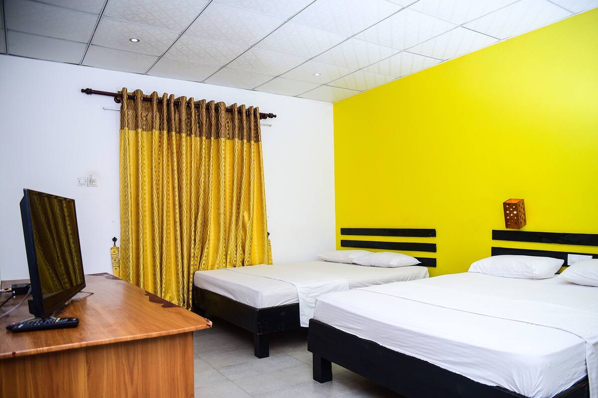 A hotel room with two beds, a desk with a computer, and a curtain.
