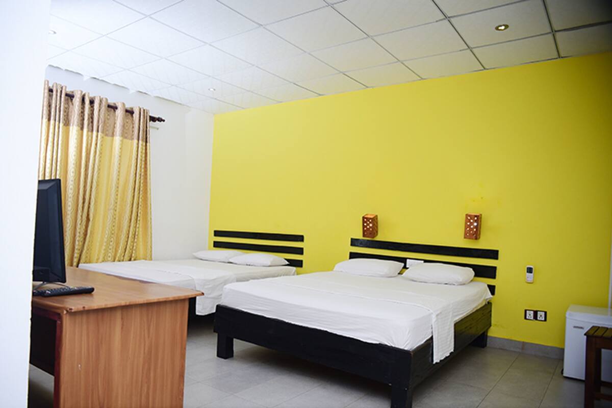 A room with two beds, a desk, a television, and a small refrigerator.