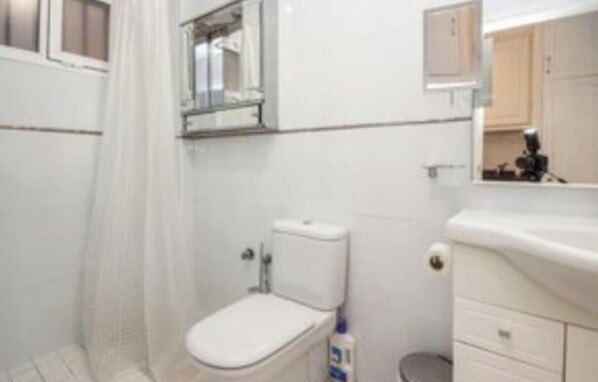 A bathroom with a toilet, a sink, and a mirror. - Rosa del Vientos Stylish studio right on beach (Malaga)